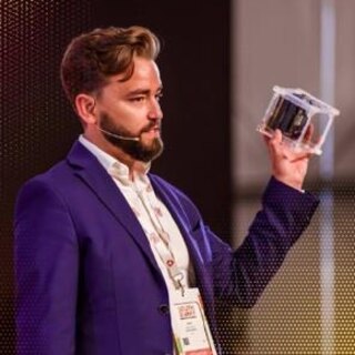 Dr. Daniel Pérez holding a CubeSat on stage